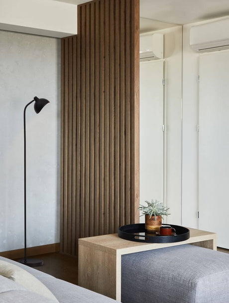 Lampe sur pied Geti Noir, Or dans un espace de vie moderne avec du bois clair et un aménagement minimaliste.