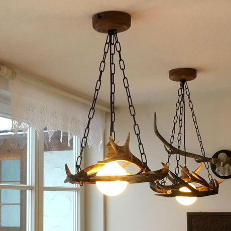 Geweih Chalet Pendellampe Ø 50cm in stilvollem Raum mit zwei Leuchten und Kettenhängern.