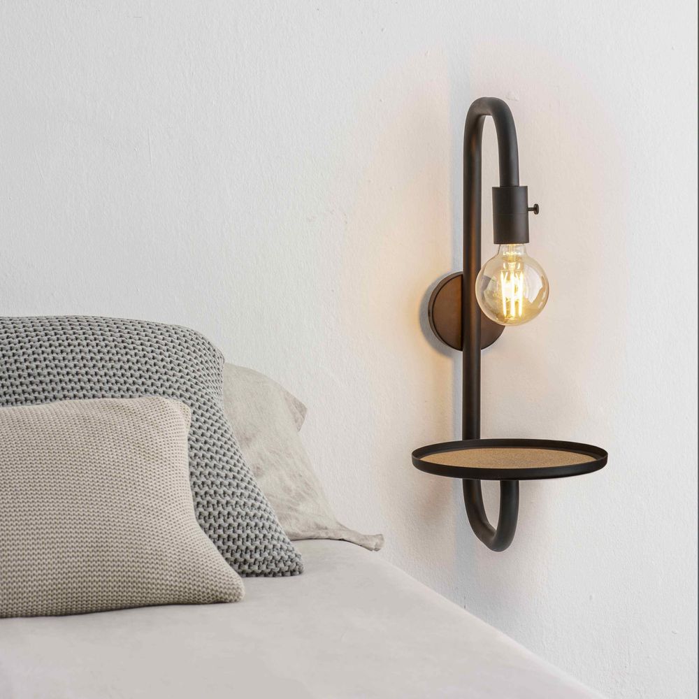Guest Bett-Wandlampe mit Ablage Schwarz neben einem Bett, beleuchtet mit einer Glühbirne.