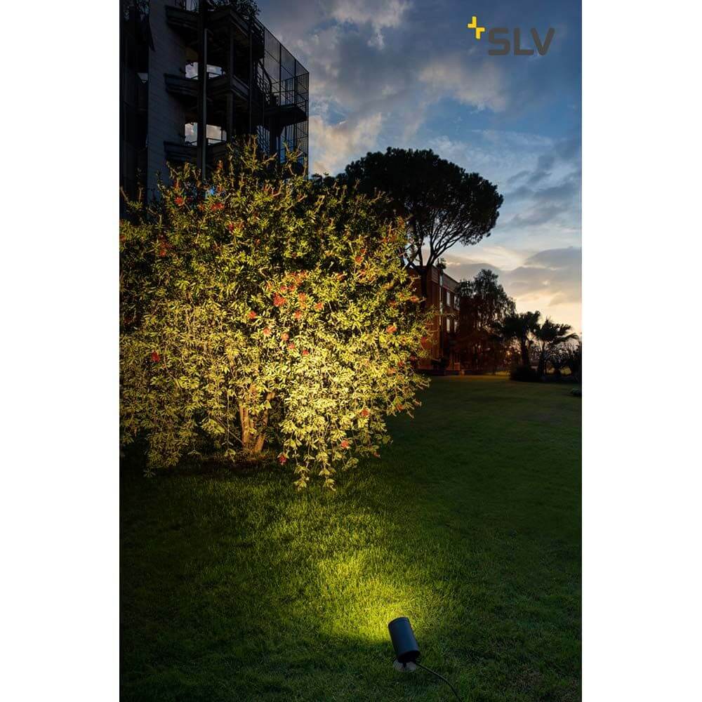 Helia Outdoor Wege- und Standleuchte LED 3000K Rund Anthrazit bei Nacht im Garten mit einer beleuchteten Pflanze.