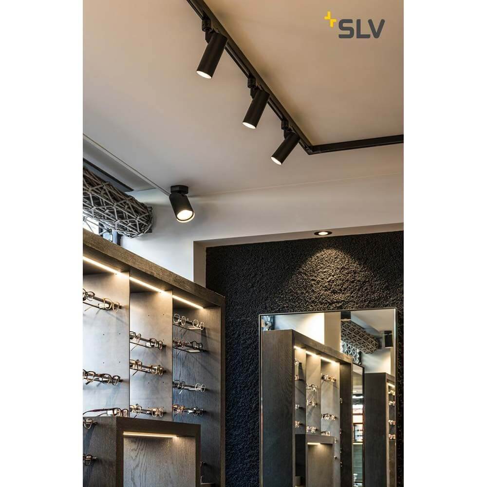 Moderne Helia 50 LED Strahler in schwarzer Farbe, montiert an einer 3Phasen-Stromschiene in einem eleganten Geschäft.