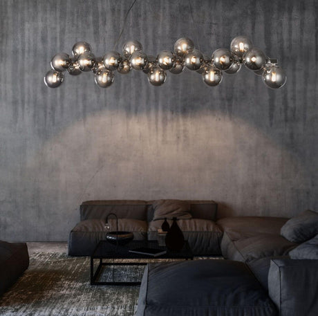 Modern dining table lamp Glob 120 cm chrome 25 smoke glasses above a modern living room with sofa.