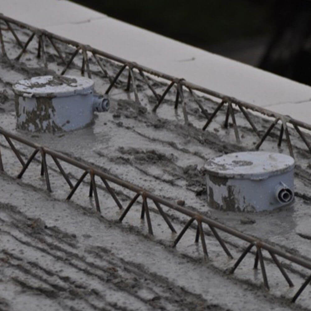 Bodenbelag mit zwei Mörteldosen und Stahlträgern auf einer Betonoberfläche.