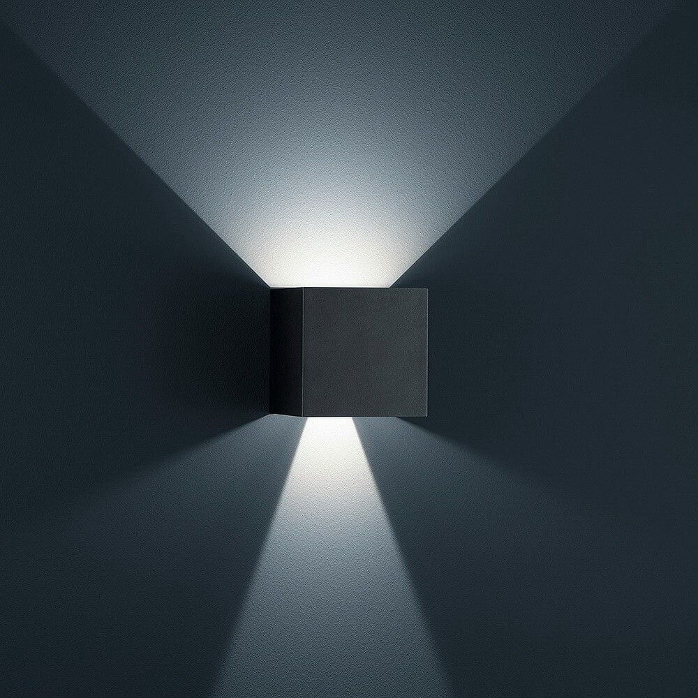 LED Außen-Wandlampe Siri 44 - L IP54 Schwarz an einer Wand mit sanftem Lichtstrahl.