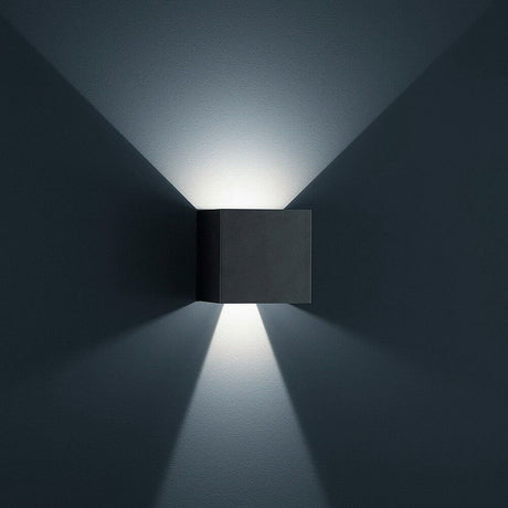 LED Außen-Wandlampe Siri 44 - L IP54 Schwarz an einer Wand mit sanftem Lichtstrahl.
