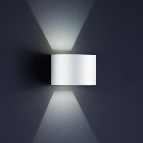 LED Udendørs væglampe Siri 44 - R IP54 Hvid monteret på en grå væg, lysstråler spredes.