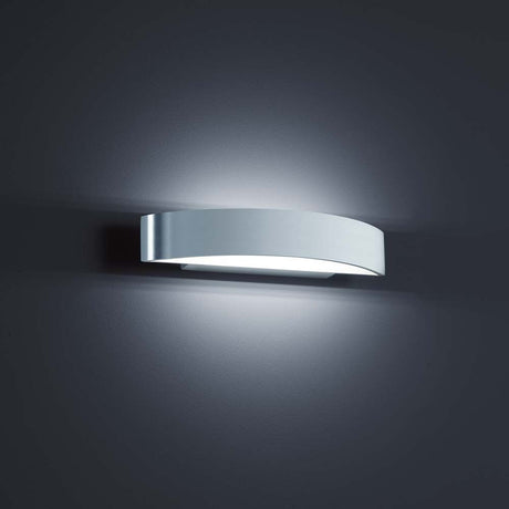 Vegglampe Yona i polert aluminium, hvit, på en moderne vegg, elegant opplyst.