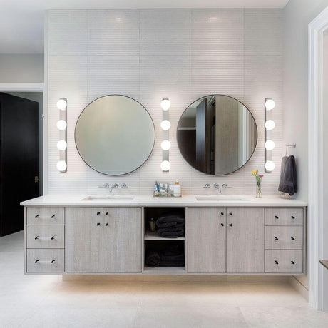 Elegantes Badezimmer mit LED Bad-Wandlampe Lis 4-flammig Chrom über runden Spiegeln und modernem Waschtisch.