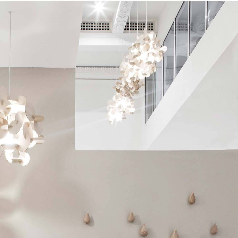 Holz-Pendelleuchte Bau S 44cm in modernem Raumdesign hängend über minimalistischer Wand.