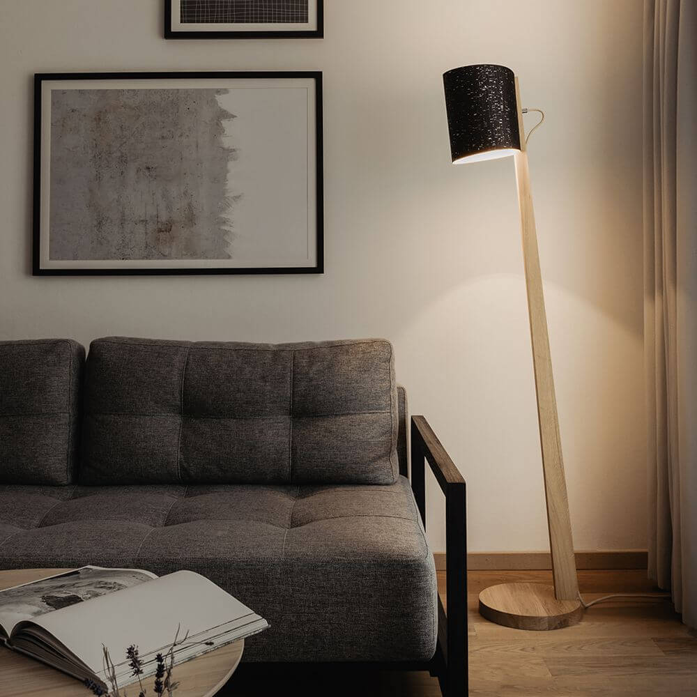 Holz Stehlampe mit Schirm Zylindrisch 167cm steht neben einem modernen Sofa in einem stilvollen Wohnzimmer.
