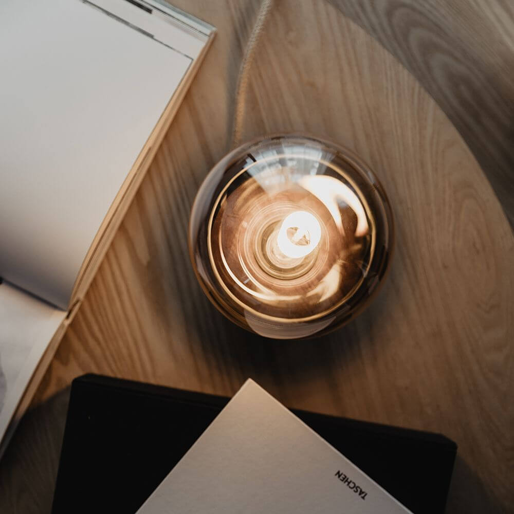 Holz Tischlampe Ø 11cm in 3 Holzarten auf einem Holzoberfläche mit Büchern.