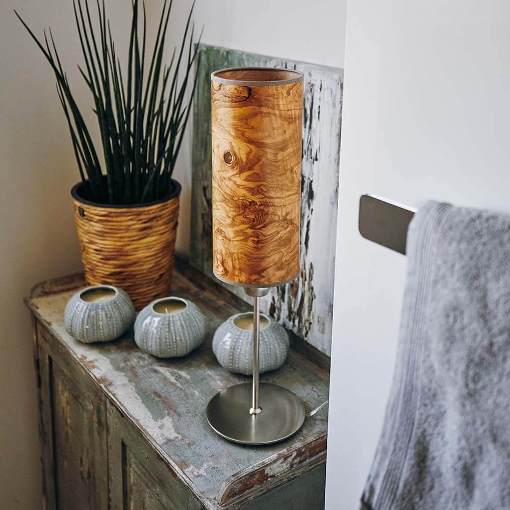 Holz-Tischlampe Arboreus 50cm Olivesche-Maser auf einem Tisch mit Pflanzen und Dekoration