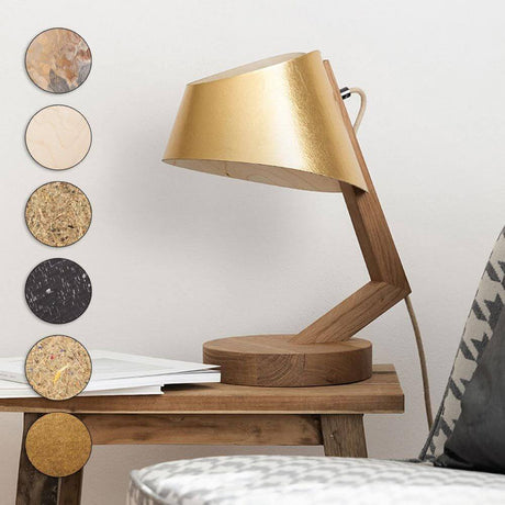 Holz Tischleuchte mit Schirm geschwungen in goldfarbenem Design auf einem Holztisch.