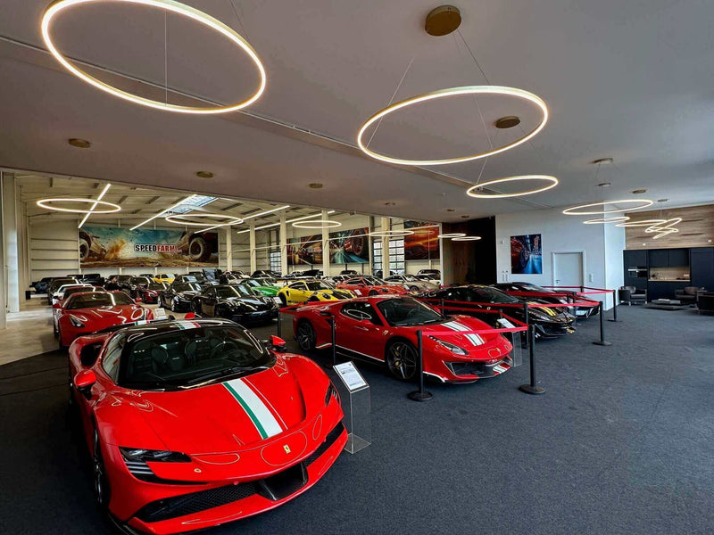 Schicke Ferrari und andere Sportwagen in einer modernen Showroom-Umgebung mit stilvollem Lichtdesign.