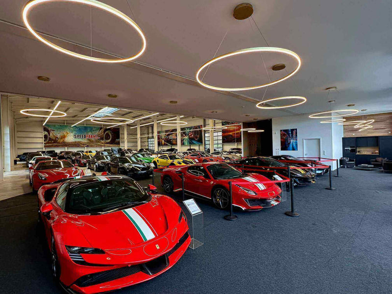 Schicke Ferrari und andere Sportwagen in einer modernen Showroom-Umgebung mit stilvollem Lichtdesign.