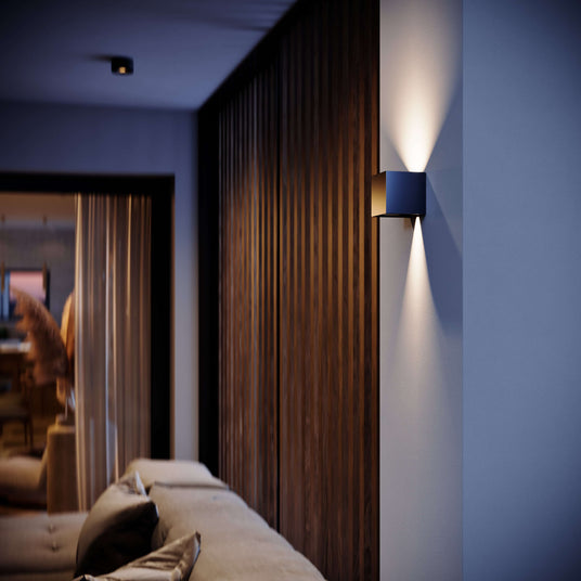 Moderne Wandlampe in einem stilvollen Wohnzimmer mit Holzverkleidung am Abend.