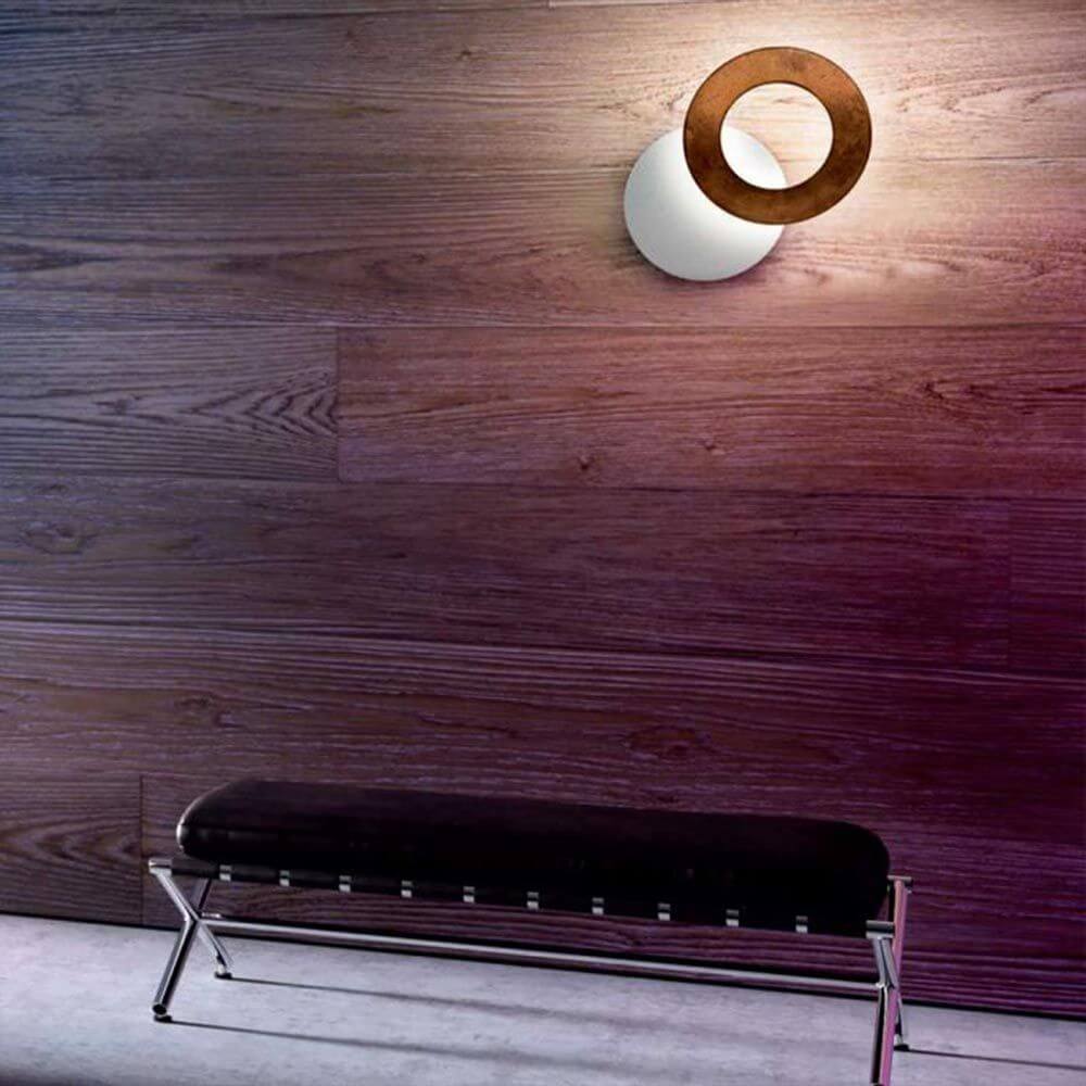 Icone LED Wandleuchte Vera Ø 26cm in Weiß mit Rost auf einer Holzwand, ideal für Wohnzimmer oder Schlafzimmer.