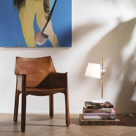 Modern Axel wooden table lamp next to a wooden chair and stack of books, stylish interior design.