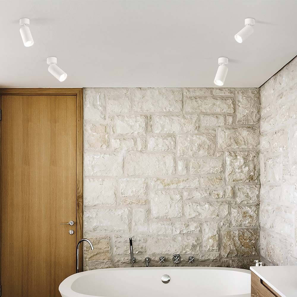 Dynamite Deckenspot für stilvolle Beleuchtung im modernen Badezimmer mit Steinmauern und freistehender Badewanne.