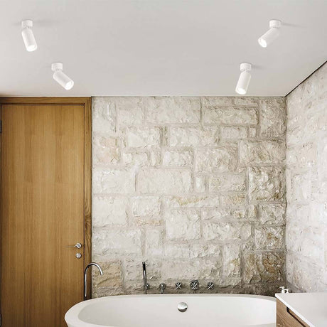 Dynamite Deckenspot für stilvolle Beleuchtung im modernen Badezimmer mit Steinmauern und freistehender Badewanne.