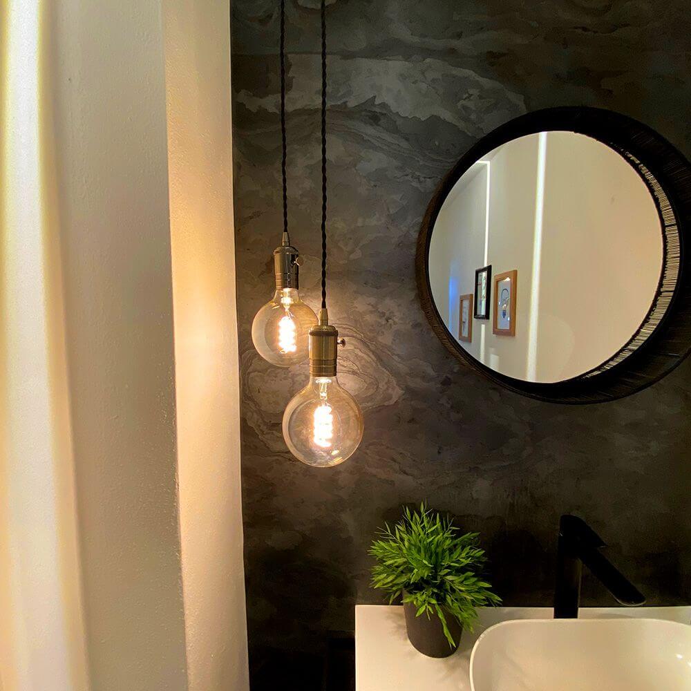 Hängelampe Doc Sp1 Retro Altmessing in einem modernen Badezimmer mit Spiegel und Pflanzen.