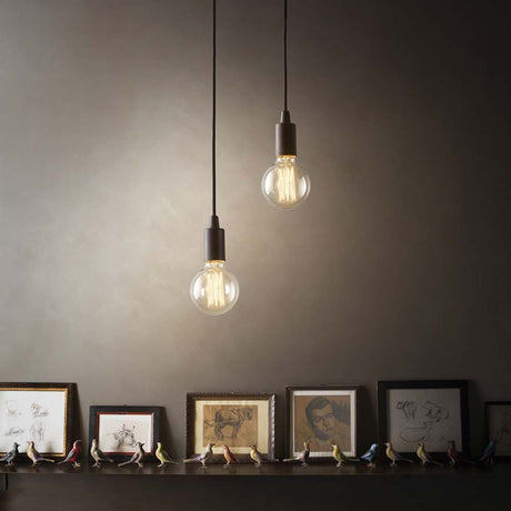 Hängeleuchte Edison Sp1 Schwarz mit zwei Glühbirnen über einem Regal mit Bildern.