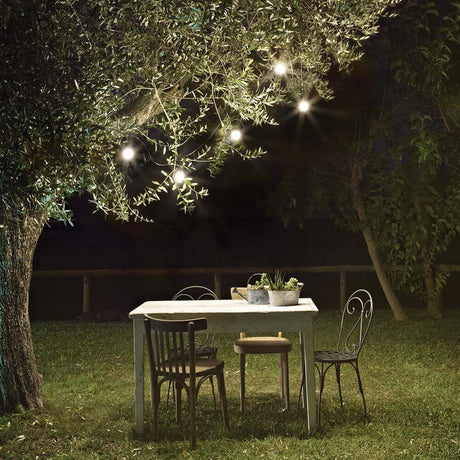 5 flg. Lichterkette Fiesta Sp5 für Außen Schwarz an einem Tisch unter einem Baum im Garten.