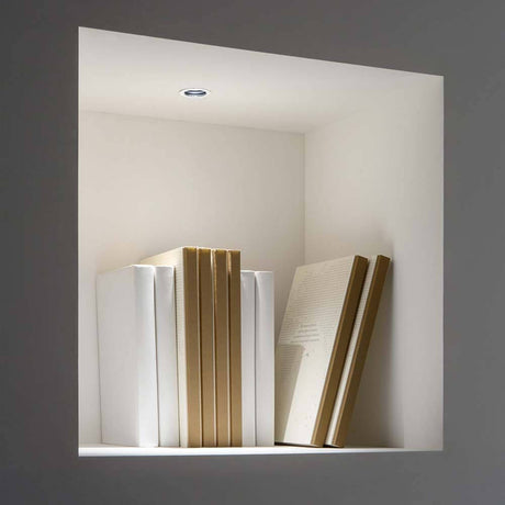 One LED Einbauspot beleuchtet moderne Bücher in einem eleganten Regal.