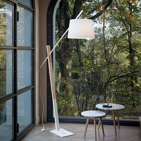 Moderne gulvlampe Eminent White ved siden af et vindue med udsigt over landskabet.
