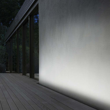 Thor LED Bodenleuchte IP65 beleuchtet eine moderne Wand auf einer Holzterrasse.