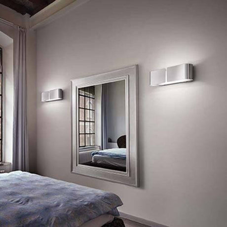 Applique murale Clip Ap2 Mini blanche sur un mur à côté d’un miroir dans la chambre à coucher.