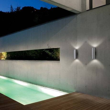 Wall light Gun Ap2 Large Aluminium on a modern wall next to a lit pool.