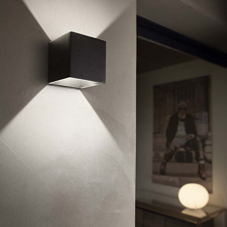 Wall light Rubik Ap1 black on the wall, modern design with soft lighting.