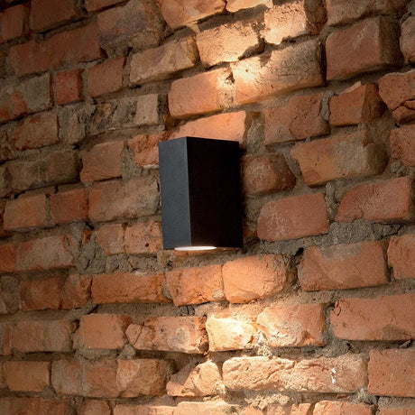 Schwarze Wandleuchte Up Ap2 in rechteckiger Form an Ziegelmauer montiert, warmes Licht abstrahlend