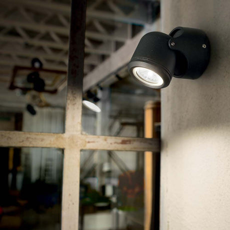 Wandleuchte Xeno Ap1 Schwarz an einer Wand montiert, beleuchtet einen Innenraum, modernes Design.