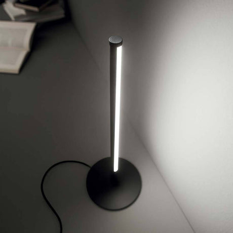 Lampe de table Yoko LED en métal sur une table, design moderne avec fine bande lumineuse en noir.