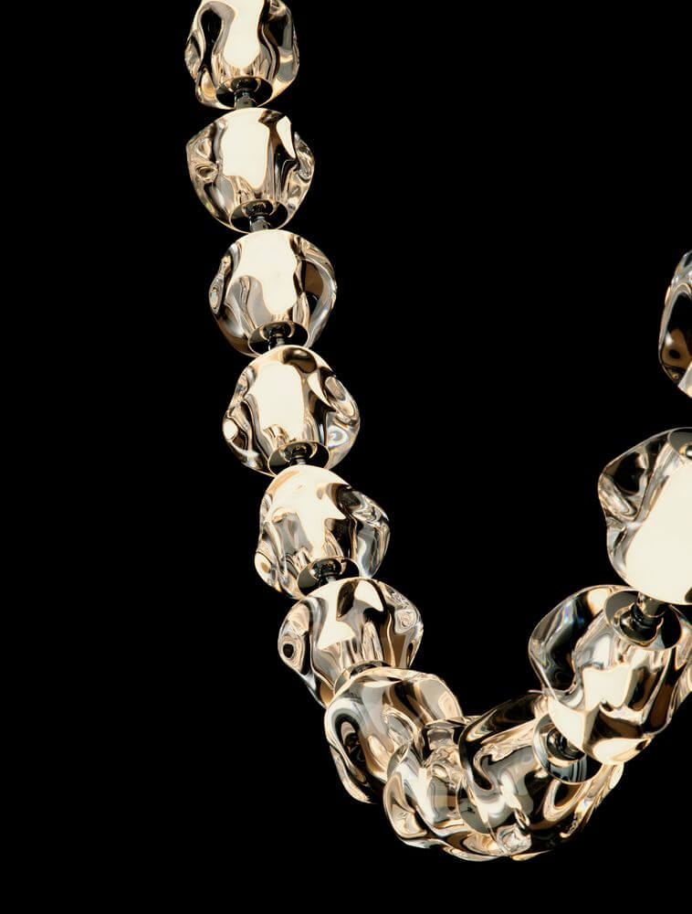 Hochwertige Halskette aus transparenten und goldenen Glaselementen auf schwarzem Hintergrund.