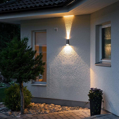 Luminária de parede exterior Imola LED com feixe de luz duplo em antracite numa parede da casa, ilumina a entrada.