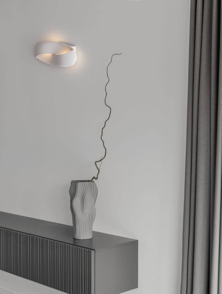 Infinity LED Wandleuchte 3000K Weiß an einer Wand mit moderner Vase und stylischem Interieur.