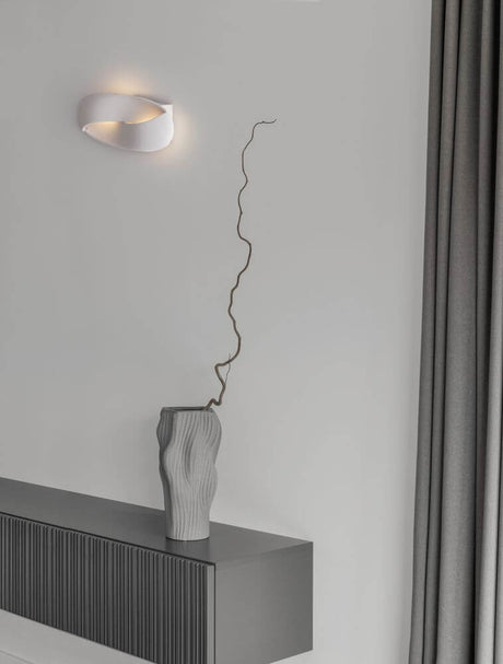 Infinity LED wall light 3000K white on a wall with a modern vase and stylish interior.
