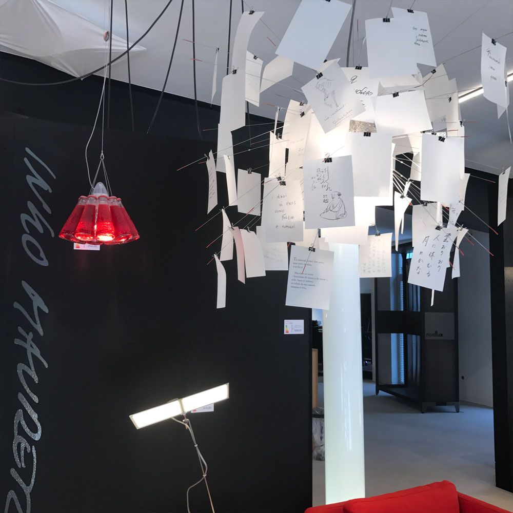 Ingo Maurer Hängelampe Campari Light mit roten Flaschen und skizzierten Blättern, modernes Design im Innenraum.