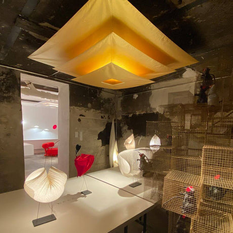 Ingo Maurer LED Plafonnier Lil Luxury dans une pièce élégante avec une voile dorée et des meubles design modernes.