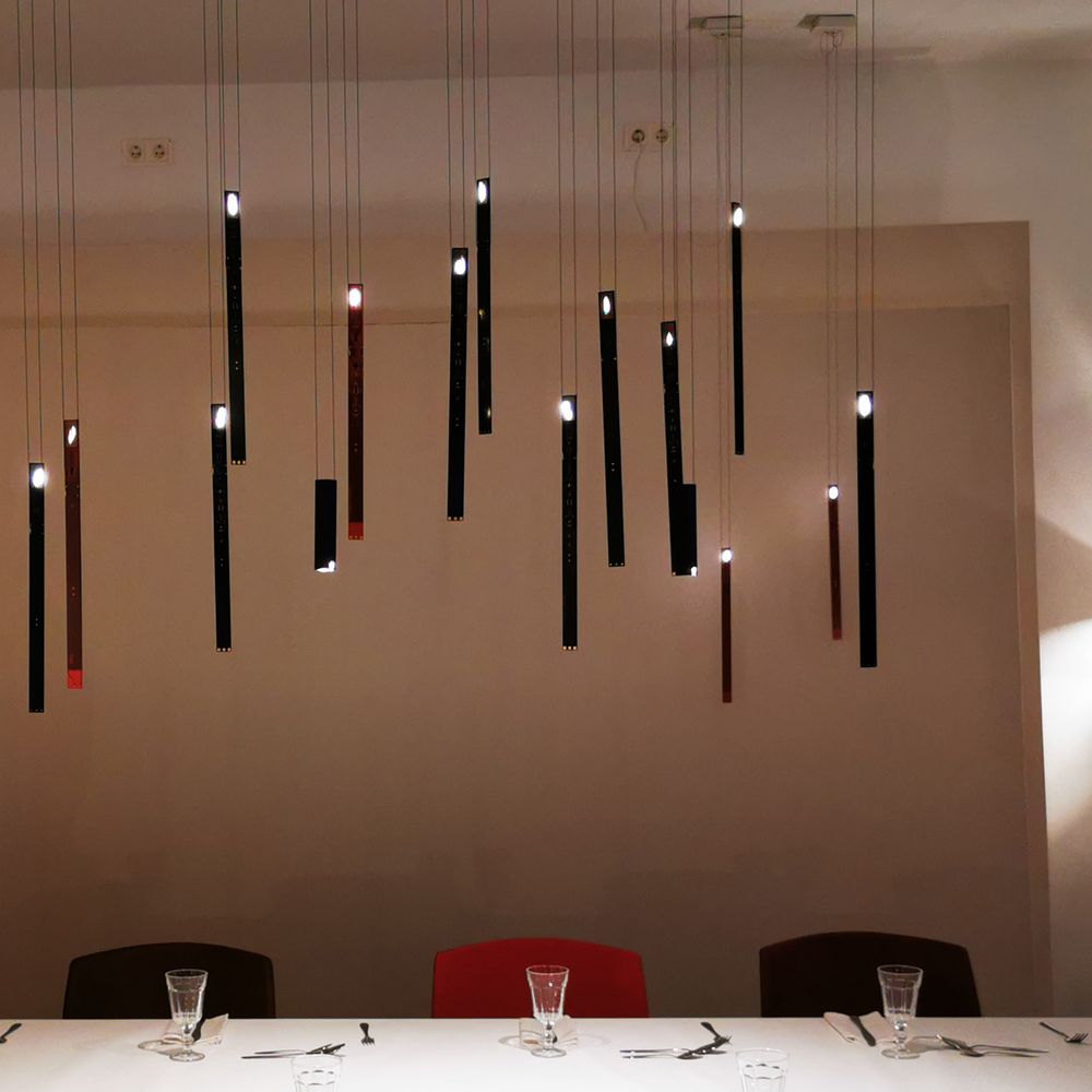 Moderne LED Hängeleuchte One New Flame von Ingo Maurer über einem eleganten Esstisch.