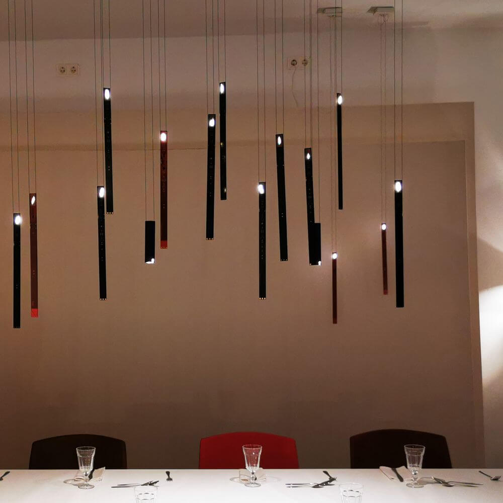 Ingo Maurer LED Hängeleuchte One New Flame in modernem Restaurant mit eleganter Tischdeko.