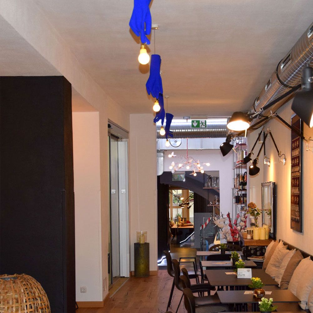Innenansicht eines Cafés mit blauen Gummihandschuhen als Pendelleuchten und gemütlicher Atmosphäre.