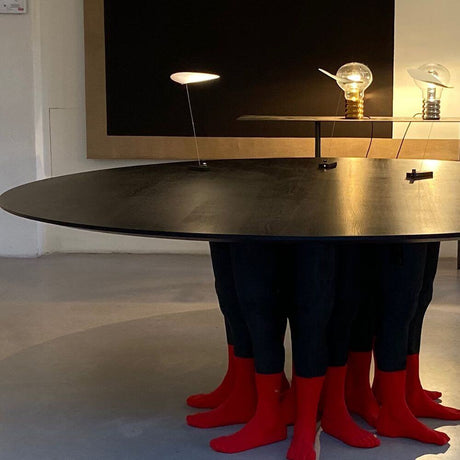 Ingo Maurer LED Tischleuchte Koyoo Akkulampe auf einem Tisch mit roten Socken und einzigartigen Lichtobjekten.
