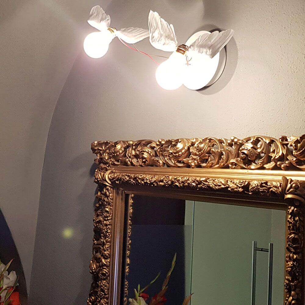 Ingo Maurer LED Wand- & Deckenlampe Lucellino Doppio mit geflügelten Glühbirnen und goldener Spiegelumrandung.