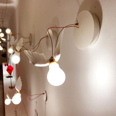 Ingo Maurer LED Lucellino wall light with feathers mounted on a wall, white light and flyable light bulbs.