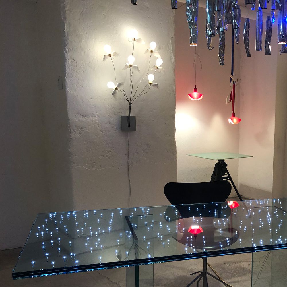 Moderne Raumgestaltung mit Ingo Maurer Wandlampe Seven off the Wall, dekoriert mit stilvollem Glas-Esstisch und weiteren Leuchten.