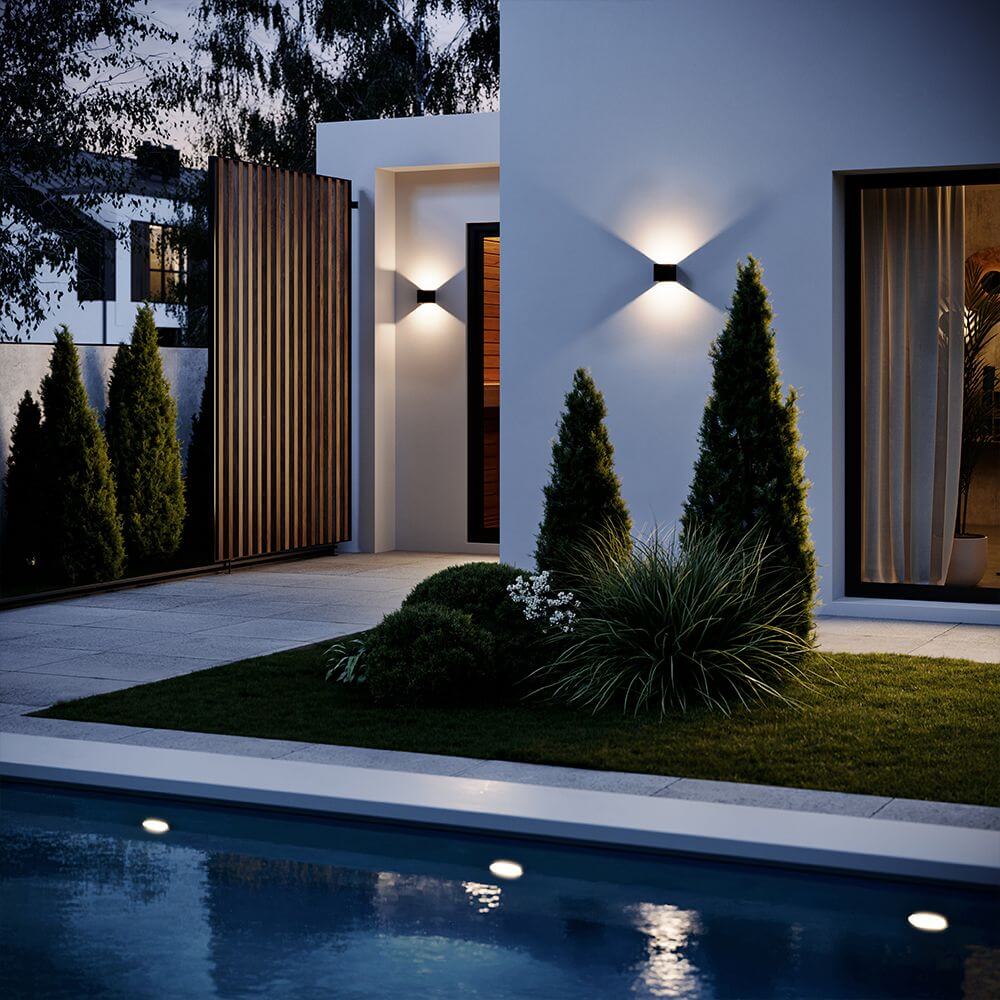 s.luce Ixa LED wandlamp met bewegingssensor aan moderne gevel met tuinverlichting.